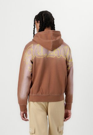 Brown hooded sweatshirt with yellow graphic text, lighter gradient sleeves, ribbed cuffs, and hem. Fabric appears soft and textured.