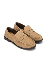 Wildleder-Pantoletten in hellbeige mit gesticktem Design und einem gewebten Akzent am oberen Teil. Flache braune Gummisohle, abgerundete Zehenpartie und bequeme Passform.