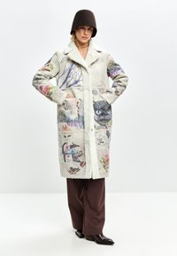 Quilted Mantel in hellem Creme mit bunten, illustrierten Mustern. Verfügt über einen Kunstfellkragen, zwei Fronttaschen und eine lässige Passform.