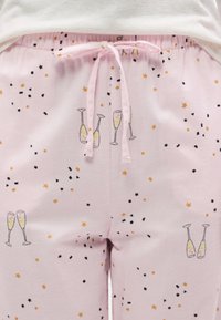 Ροζ παντελόνι πιτζάμας με κορδόνι στη μέση, διακοσμημένο με σχέδιο από ποτήρια σαμπάνιας και κομφετί σε μαύρες και χρυσές αποχρώσεις.