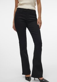 Zwarte flared jeans van denim. Heeft een fitted taille, een vijf-pocket ontwerp en nette stiksels. Draagt samen met een geribbelde top en hakken.