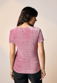 Roze top met korte mouwen en een gestructureerd, geribbeld ontwerp. Voorzien van een ronde halslijn en een licht aangesloten silhouet.