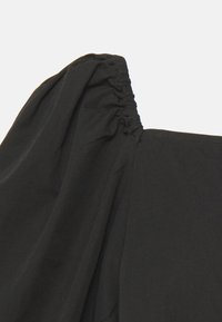 Top preto sem alças com detalhes franzidos na gola e mangas bufantes, feito de tecido suave. Textura lisa.