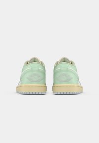 Ζευγάρι χαμηλών αθλητικών παπουτσιών σε παστέλ πράσινο με μπεζ σόλες, εμφανιζόμενο από πίσω σε λευκό φόντο.