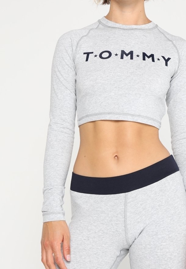 Graues, tailliertes Langarmoberteil mit dem Aufdruck "TOMMY" in Marineblau, kombiniert mit passenden grauen, hoch geschnittenen Leggings mit einem marineblauen Bund.