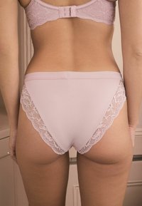 Chiloți roz deschis, cu accente de dantelă pe laterale, textură netedă și un design ajustat. Talie elastică pentru confort.