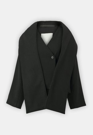 Veste noire en tissu texturé, avec décolleté en V, fermeture à un bouton et manches larges. Design minimaliste, sans motifs visibles.