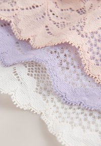 Trei straturi de dantelă cu margini ondulate în bej, lavandă și alb, fiecare cu modele florale și geometrice complexe.