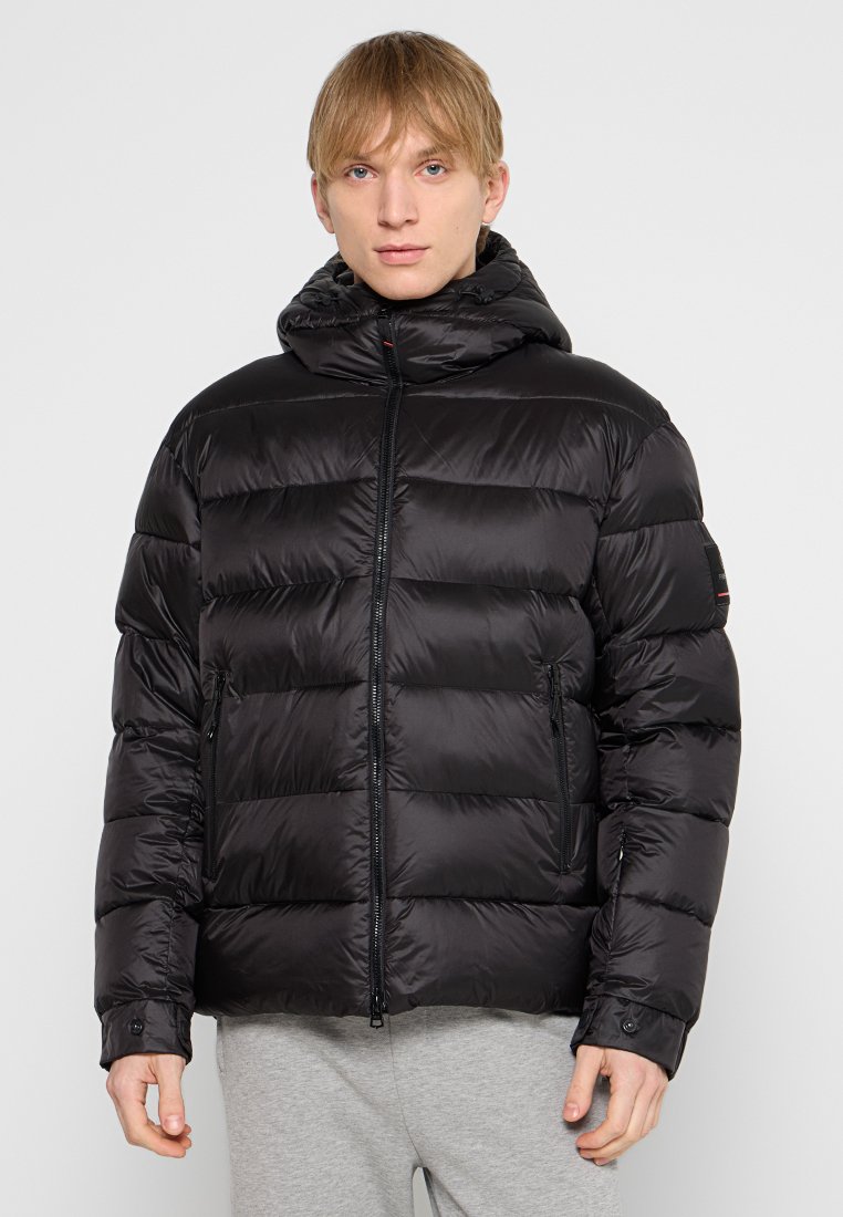 Schwarze Puffjacke mit Kapuze, ausgestattet mit einem gesteppten Design, einem Reißverschluss auf der Vorderseite und zwei Seitentaschen. Hergestellt aus einem glänzenden, leichten Stoff.
