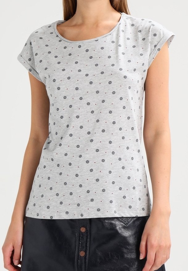Femme portant un haut gris clair à manches courtes avec de petits motifs d'étoiles noires et une jupe en cuir noire avec des boutons visibles.