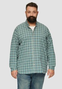 Langemouwige overhemd met knopen in een teal en marineblauw ruitpatroon. Bevat een spread collar en een licht textuur, gecombineerd met blauwe denim jeans.