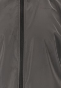 Svart vattensäker jacka gjord av ett slitstarkt material, med en central dragkedja och ordet "ENDURANCE" tryckt i en diskret design.