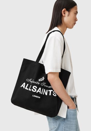 Czarna bawełniana torba na ramię z białym napisem, zawierająca loga "ALLSAINTS" i "LONDYN". Zaprojektowana w strukturalnym kształcie i z wytrzymałymi szelkami.