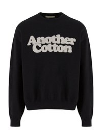 Sudadera negra de algodón, con un logo texturizado y en relieve en blanco que dice "Another Cotton" en el frente. Puños y dobladillo acanalados.