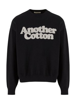 Crna dukserica od pamuka, s reljefnim bijelim logotipom "Another Cotton" na prednjoj strani. S pletivom na rukavima i rubu.