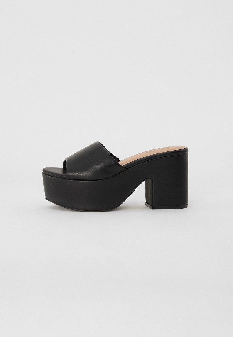 Black platform mule with an open toe, smooth leather upper, and chunky block heel. Features a minimalistic design and a beige insole.