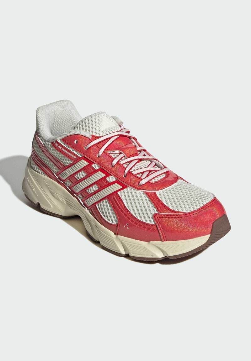 Sneaker atletico rosso e bianco con tomaia in rete, suola in gomma, colletto imbottito e accenti riflettenti. Presenta lacci e cuciture evidenti.