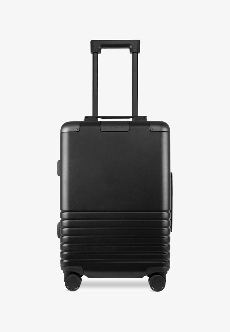 Schwarzer Hartschalenkoffer mit vertikal geripptem Muster, ausziehbarem Griff und vier Rädern für Mobilität. Besitzt strapazierfähiges Material und einen seitlichen Griff.