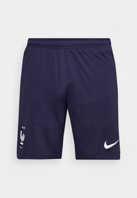Ciemnoniebieskie spodenki sportowe z elastycznym paskiem w talii, z białym logo Nike po prawej stronie i srebrnym symbolem koguta z dwoma gwiazdkami po lewej.