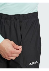 Svarta Terrex-byxor med elastisk midja och ficka med dragkedja, som har en mjuk textur och broderad logotyp på nedre benet.