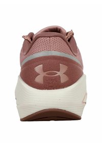 Vista trasera de una zapatilla deportiva rosa, que presenta una parte superior texturizada y una suela blanca con una banda de rodadura marrón. Logotipo de Under Armour visible.
