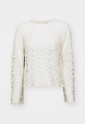 Lace long-sleeve top in off-white with circular patterns, round neckline, and a cropped design. Features delicate texture and subtle sheen.