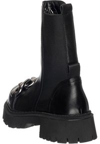 Bottines noires avec une combinaison de matériaux en cuir et en textile. Semelle en caoutchouc épaisse avec texture striée, bout rond et quincaillerie décorative.