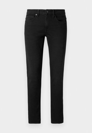 Fekete farmernadrág egyenes szabással. Cipzáras nyitással, öt zsebből és diszkrét varrásból áll. Simább textúrával és egységes színnel rendelkezik.