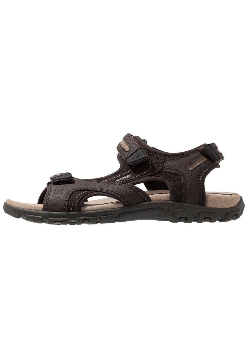 Brun sandal med flera justerbara remmar, perforerat ovandel, vadderad innersula och strukturerad gummisula för grepp och komfort.