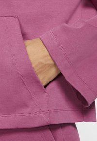 Roze sweatshirt met geribbelde manchetten en kangoeroezak. De stof heeft een gladde textuur, met zichtbare stiksels en een losse pasvorm.