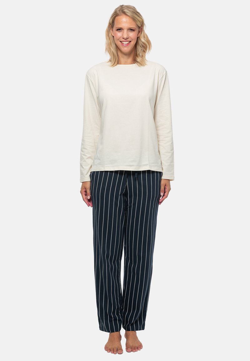 Långärmad krämfärgad topp som matchas med marinblå randiga pyjamasbyxor. Byxorna har vertikala vita ränder och en avslappnad passform.