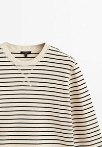 Maglione crema con righe nere orizzontali, scollatura a coste e tessuto testurizzato. Presenta un piccolo ricamo a croce sul colletto.