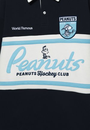 Marinblå pikétröja med en vit och ljusblå horisontell rand. Har texten "Peanuts Hockey Club" och en broderad Snoopy-logotyp.