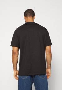 Černé tričko s krátkým rukávem, které má klasický kulatý výstřih. Vyrobeno z hladké směsi bavlny, s jednobarevným designem a minimálním švem.