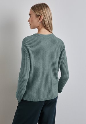 Maglione a coste in teal con maniche lunghe, scollatura rotonda e spalle basse. Morbido al tatto, lunghezza fino ai fianchi e dettagli di design minimali.
