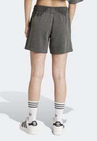 Gray cotton blend shorts with an elastic waistband, ending above the knee, worn with white socks featuring black stripes and black sneakers.