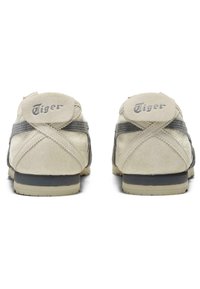 Sneakers met een beige suede bovenwerk, grijze accenten en een gestructureerde afwerking. Beschikt over een ronde neus en een platte grijze rubberen zool. "Tiger" logo op de hiel.