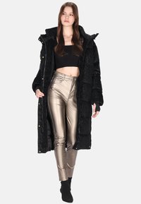 Czarna pikowana kurtka z teksturowanym wykończeniem, z kapturem i złotymi guzikami, w komplecie z błyszczącymi, dopasowanymi metalicznymi złotymi spodniami.