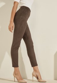 Leggings marron taille haute en texture lisse et douce avec un design ajusté. Associés à des escarpins nude à talons aiguilles pour le contraste.