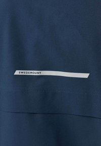 Mørkeblåt stof med en vandret hvid stribe mærket "Swedemount" nær syddelinjer.