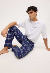 Biely bavlnený tričko s logom "Tommy Hilfiger"; modré kárované nohavice na voľný čas s červenými a bielymi pruhmi, voľný strih, elastický pás.
