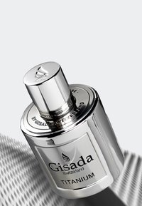 Silver cylindrical perfume bottle with a detailed top, label reading "Gisada Switzerland Titanium," featuring a reflective, smooth surface.