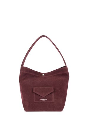 Sac à épaule en daim marron avec une bandoulière, une poche à rabat avant et une petite fermeture à bouton métallique au centre supérieur.