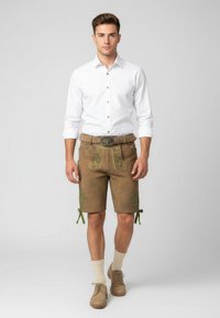 Lederhosen in pelle marrone con ricami verdi, abbinati a una camicia bianca, calze chiare e scarpe. Presenta una fibbia decorative per la cintura.
