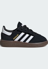 Svarte semskede sneakers med tre hvite striper, en svart gummisåle, sølvheltakk føring, og gull "Spezial" merking på siden.
