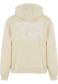 Cremefarvet hoodie lavet af blødt stof, med et stort hvidt tekstgrafik på ryggen med sætningen "Hvad går rundt kommer tilbage rundt."