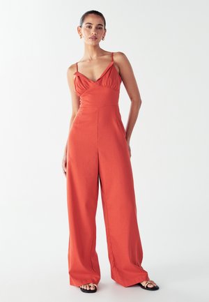 Rode, vloeiende jumpsuit met een aansluitende lijfje, V-halslijn en dunne bandjes. Ontwerp met brede pijpen, gladde textuur, casual stijl.