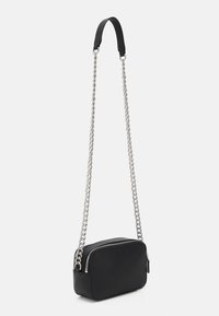 Černá obdélníková kabelka přes rameno s texturovaným povrchem, stříbrným zipem a dlouhým stříbrným řetízkovým popruhem s koženým ramenním polštářkem.