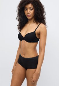 Σετ μαύρου εσωρούχου με στηθόδεσμο με πάνα και ρυθμιζόμενους ιμάντες και αντιστοιχούμενο σλιπ ψηλόμεσο με δαντελένιο τελείωμα. Λεία υφή.