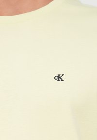 Κρέμα μπλουζάκι με στρογγυλή λαιμόκοψη και μικρό μαύρο κεντημένο λογότυπο "cK" στο αριστερό στήθος.